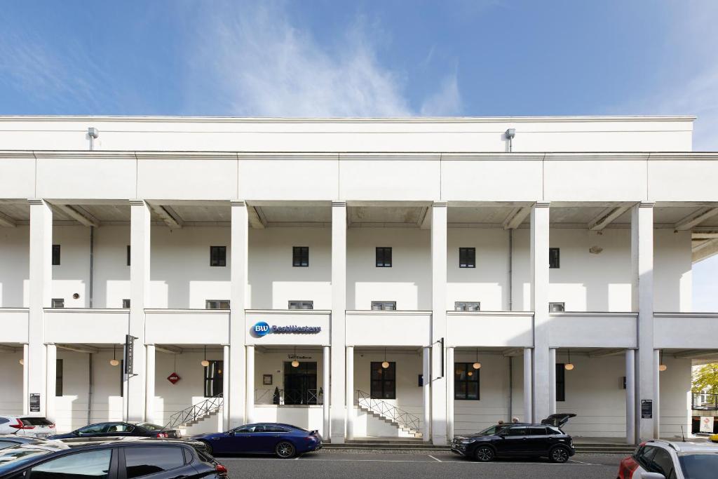 a white building with cars parked in a parking lot at Best Western ToRVEhallerne in Vejle