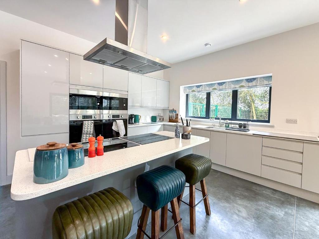 a kitchen with white cabinets and a counter with stools at 4 Bed in Acton oc-k40259 in Waldingfield