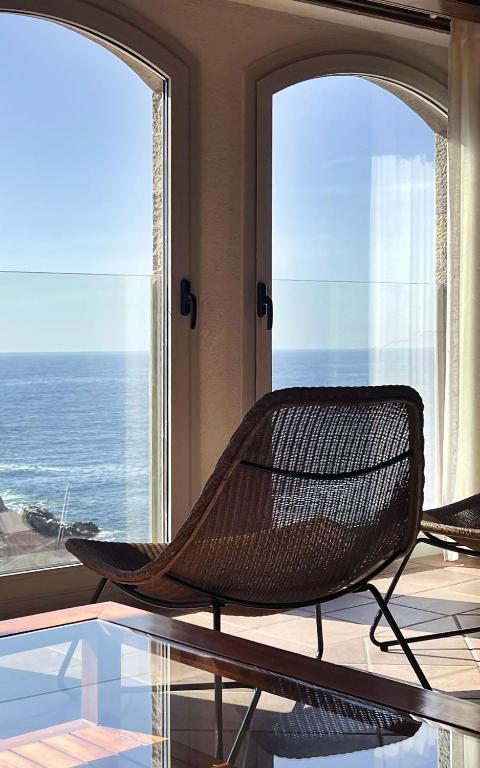 a rattan chair sitting on a table in front of windows at Luxury Rocamar – Primera Línea y Terraza in Tossa de Mar