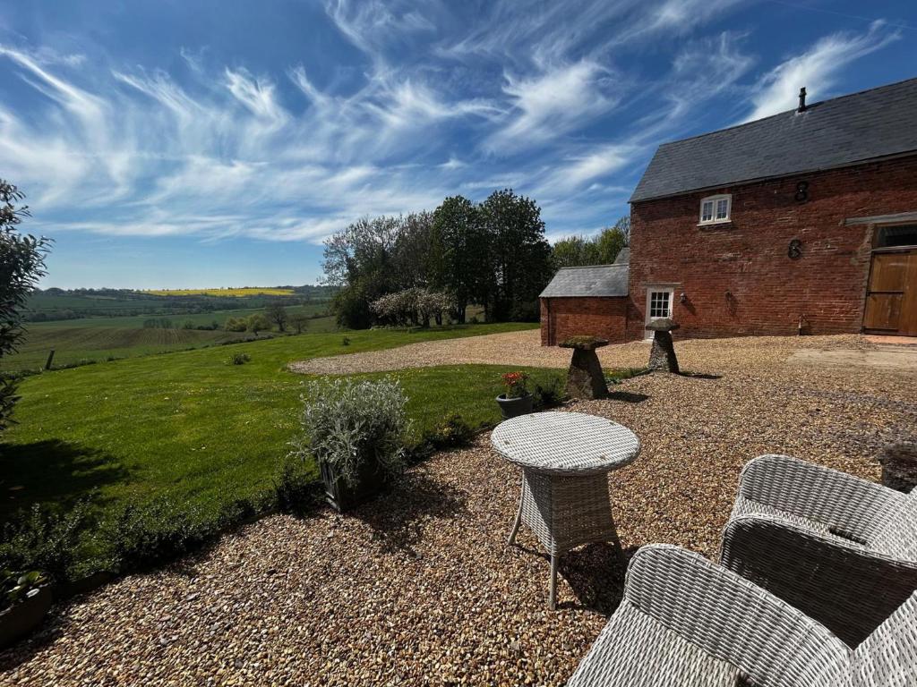 a patio with two chairs and a table and a building at The Granary Barn at America Lodge in Oakham