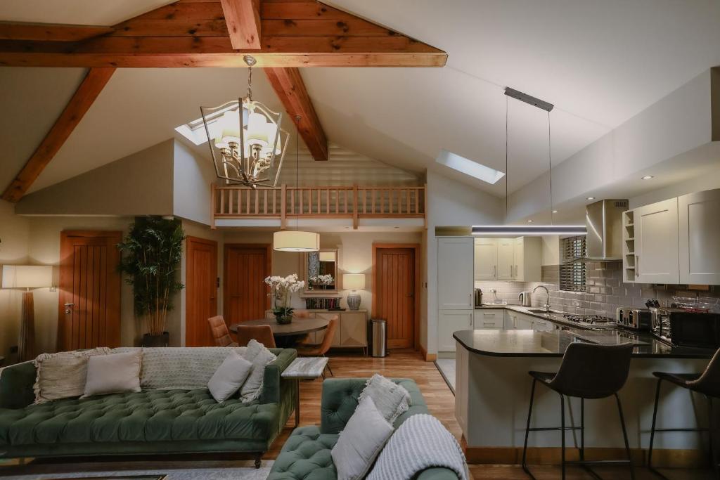 a living room with a green couch and a kitchen at Noble Fir Lodge - The Hollies Retreats in Oakmere