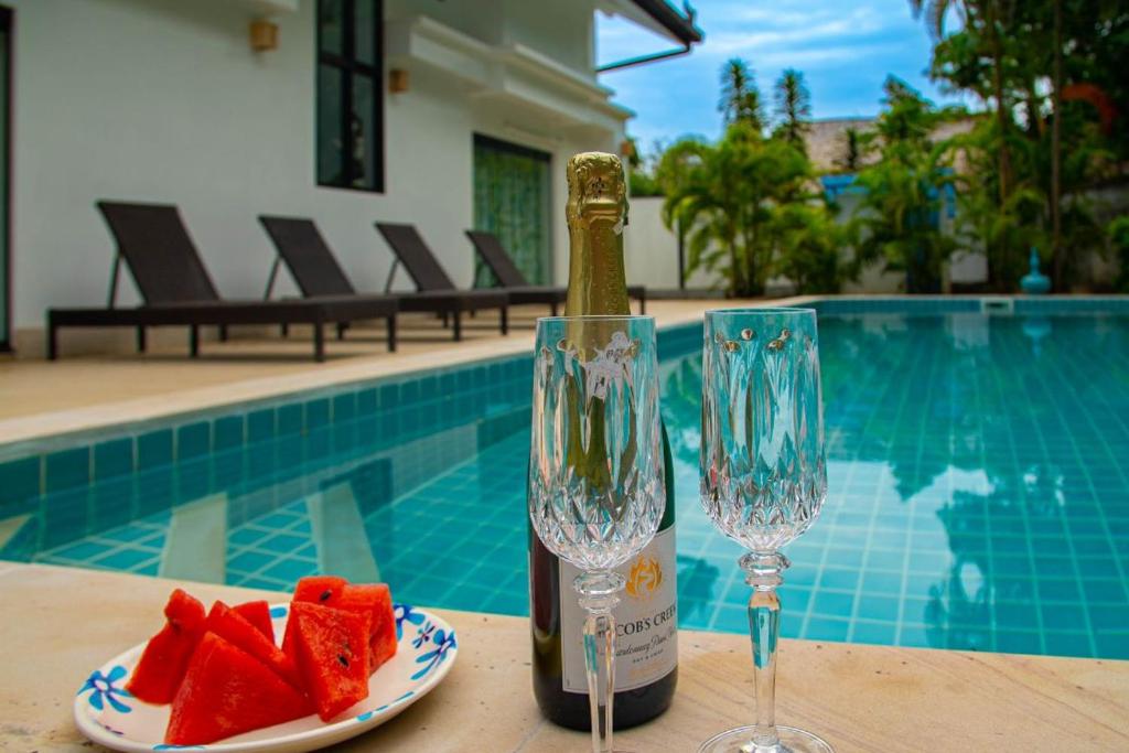 a bottle of wine and a plate of watermelon and two glasses at Malee Beach F1 in Phra Ae beach