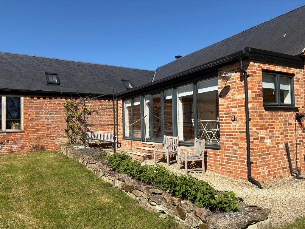 a brick house with two chairs and a patio at Hedges House in Buckingham
