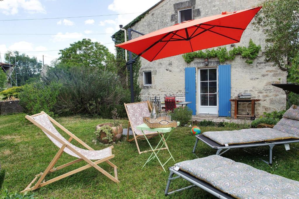 a group of chairs and an umbrella in a yard at Gîte Le Gué De Champagné in Torxé