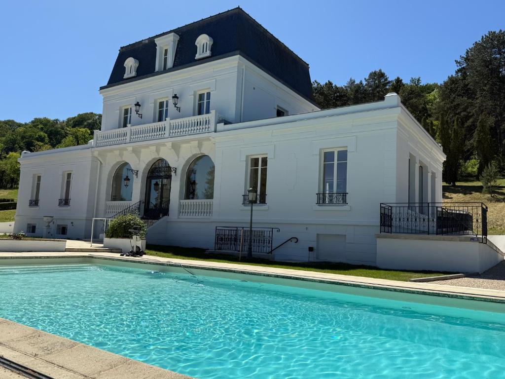 a large white house with a pool in front of it at DomaineduRocBlanc in Merey
