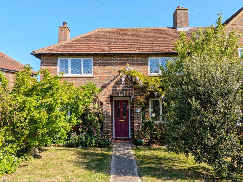a brick house with a red door and trees at Pickleberry Cottage - Close to sandy beach in West Wittering
