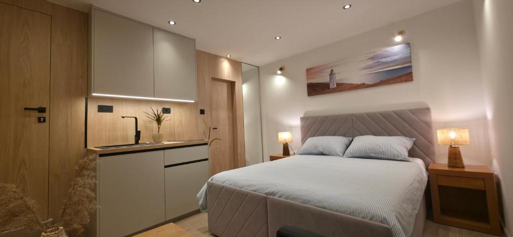 a bedroom with a white bed and a kitchen at Lighthouse Zadar Center Apartments in Zadar