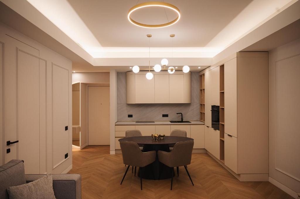 a dining room with a table and chairs and a kitchen at Designer Suite • Pool & Sauna • Pipera Metro in Bucharest