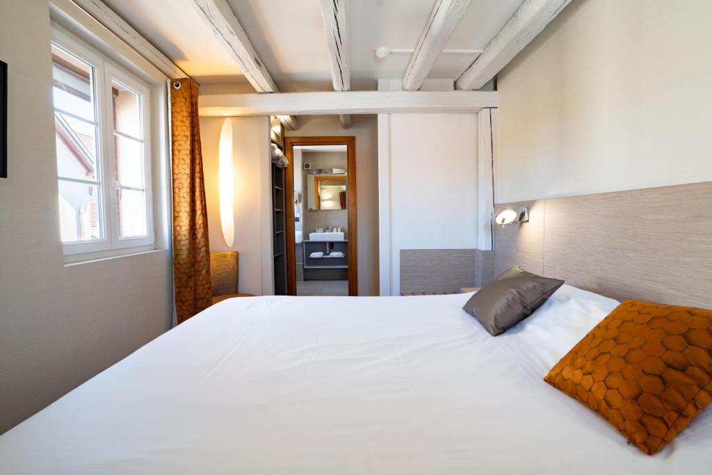 a large white bed in a room with a window at Hotel Restaurant Père Benoît in Entzheim