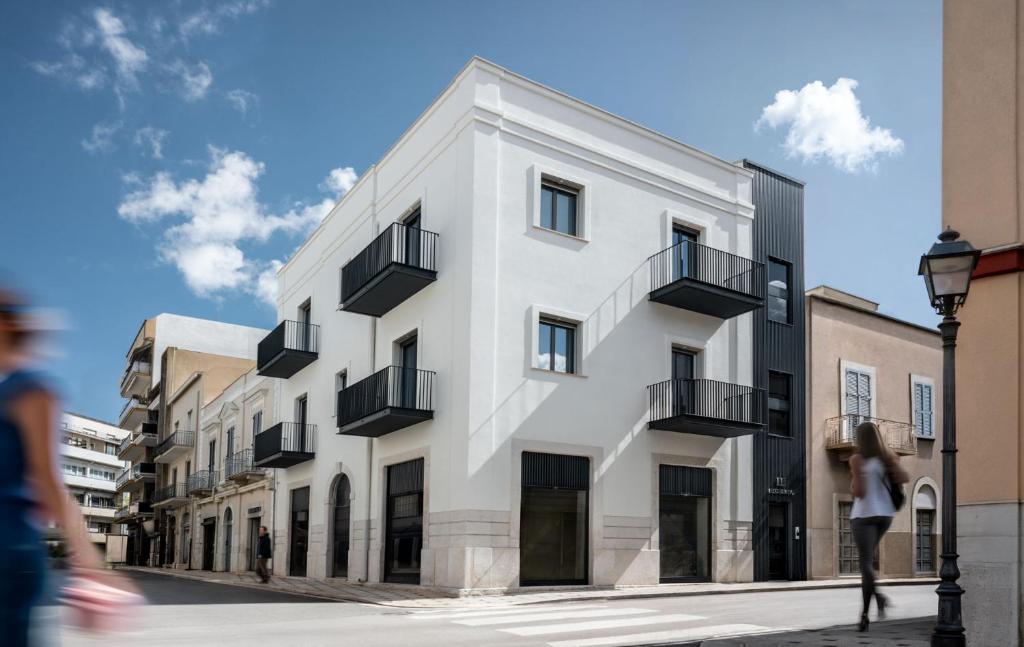 a white building with black balconies on a street at BOREMA Apulian Rooms in Andria