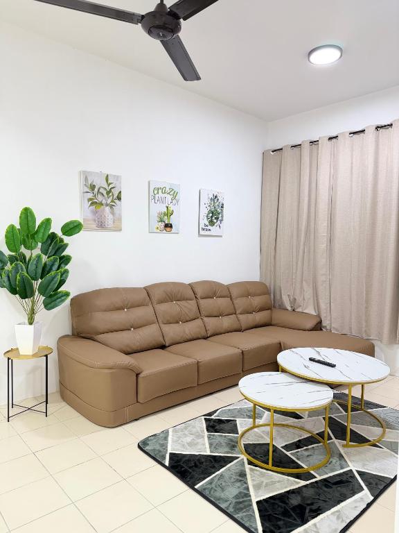 a living room with a brown couch and two tables at Nj Guesthouse in Tawau
