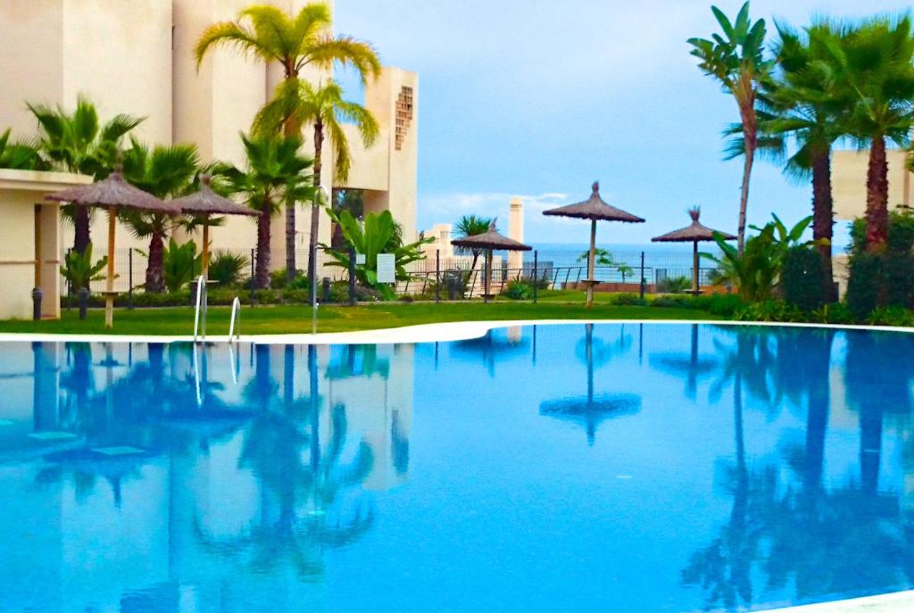 a swimming pool in front of a hotel with palm trees at Bahia De La Plata 1A in Estepona