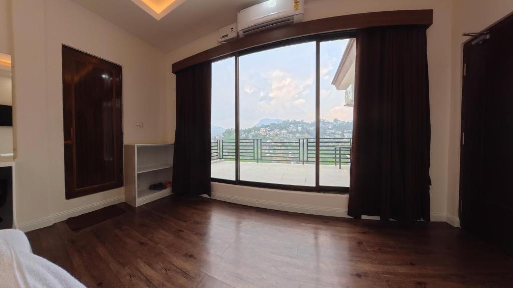 a bedroom with a large window with a view at The View Hotel Falkland in Āīzawl