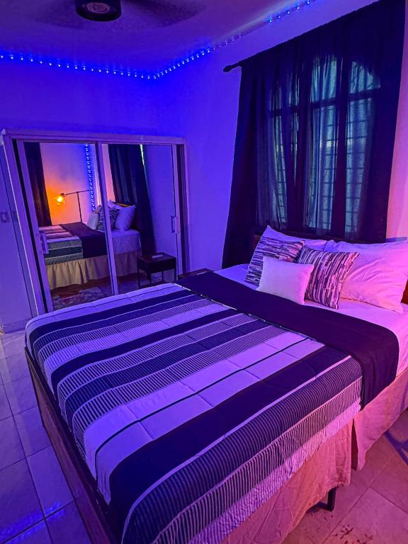 two beds in a bedroom with purple lighting at Residential Jula in Los Prados