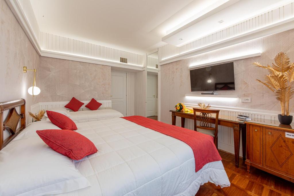 a bedroom with two beds and a desk and a television at Hotel&Ristorante Miramonti Palazzo Storico in Rieti