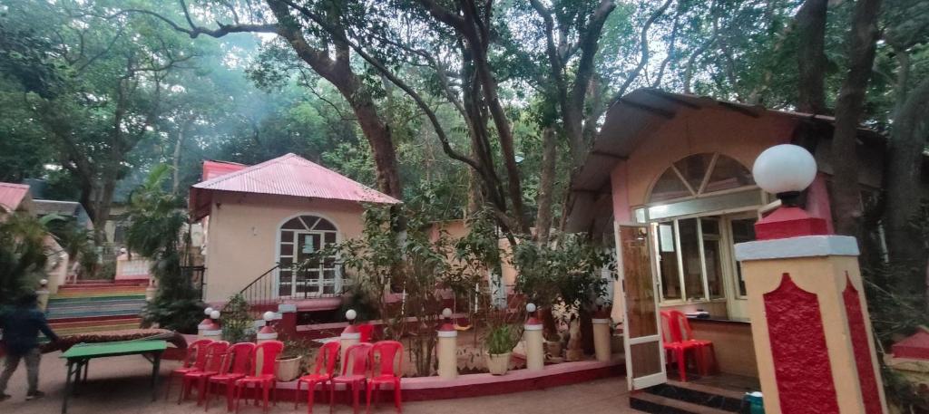 a pretend play house with red chairs in front of trees at The Wayside Inn in Matheran