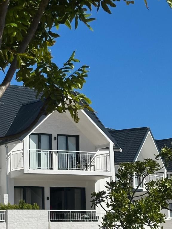 a white building with a balcony and a blue roof at St Francis Links- Gallery Deck Links Villas in St Francis Bay