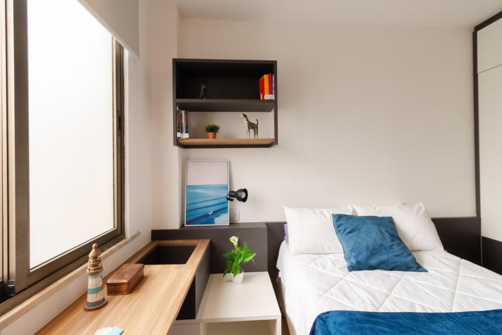 a bedroom with a bed and a desk and a window at Uliving Rio in Rio de Janeiro