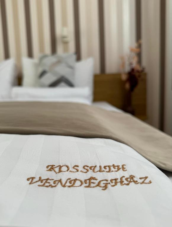 a white bed with the name of a hotel written on it at Kossuth Vendégház in Tolna