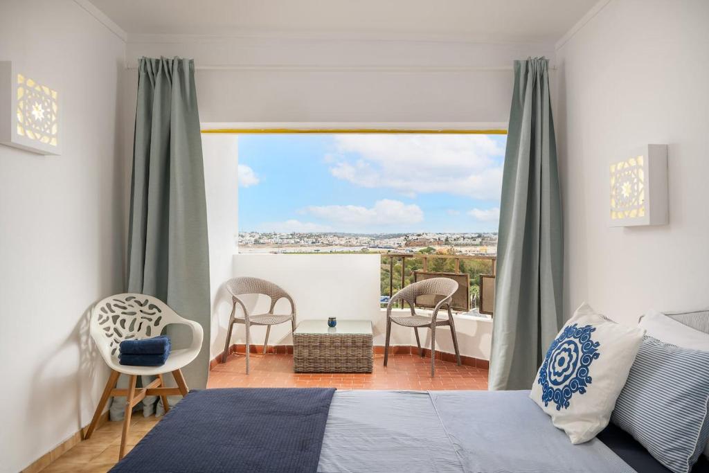 a bedroom with a bed and a balcony with chairs at Sunny Beach Praia da Rocha Sea Views Algarve in Portimão