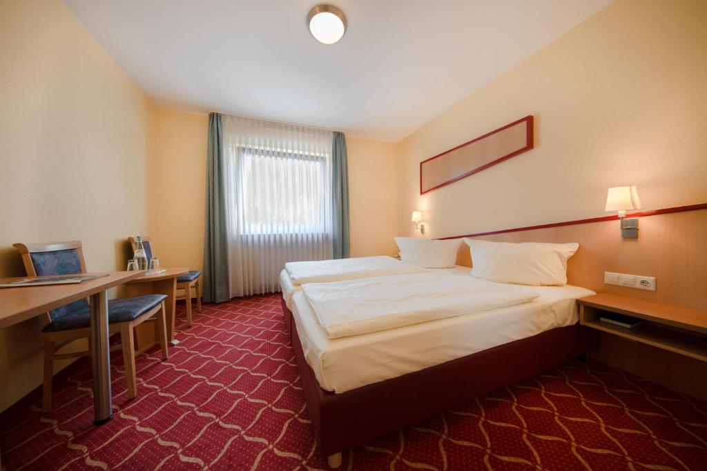 a hotel room with a large bed and a desk at Montana Hotel in Oberasbach