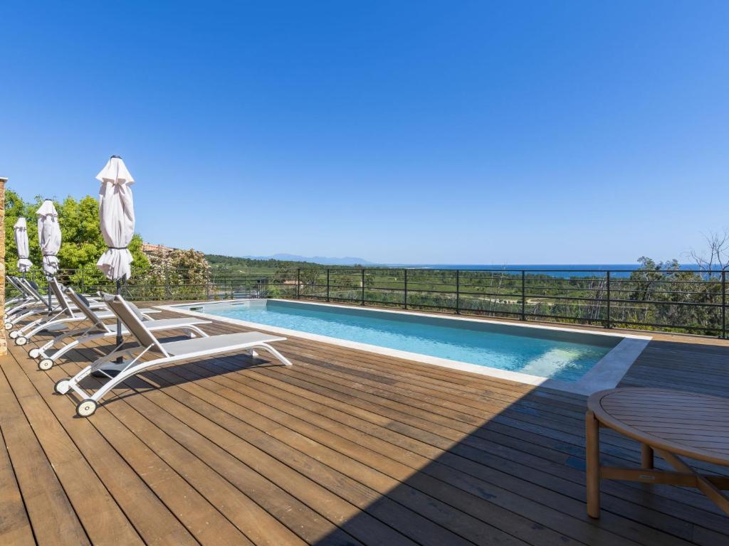a deck with a pool and chairs and a table at Villa Casa Minà by Interhome in Sari Solenzara