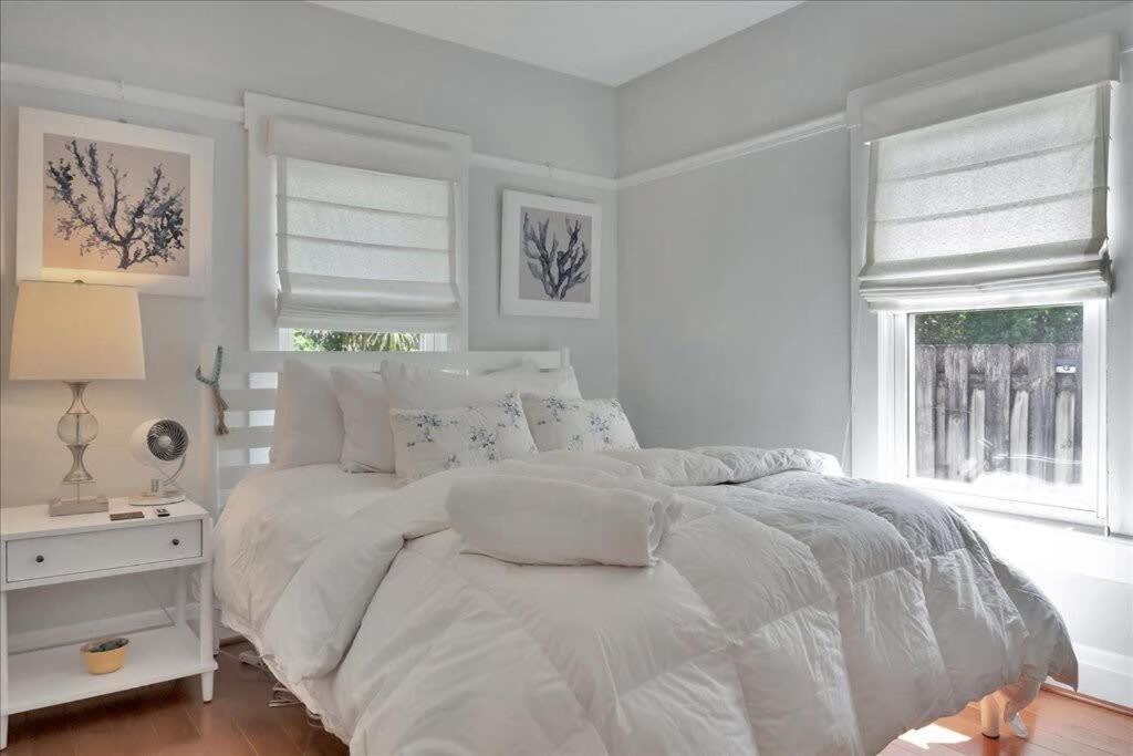 a white bedroom with a white bed and two windows at Rivercrest Bungalow Retreat in Tampa