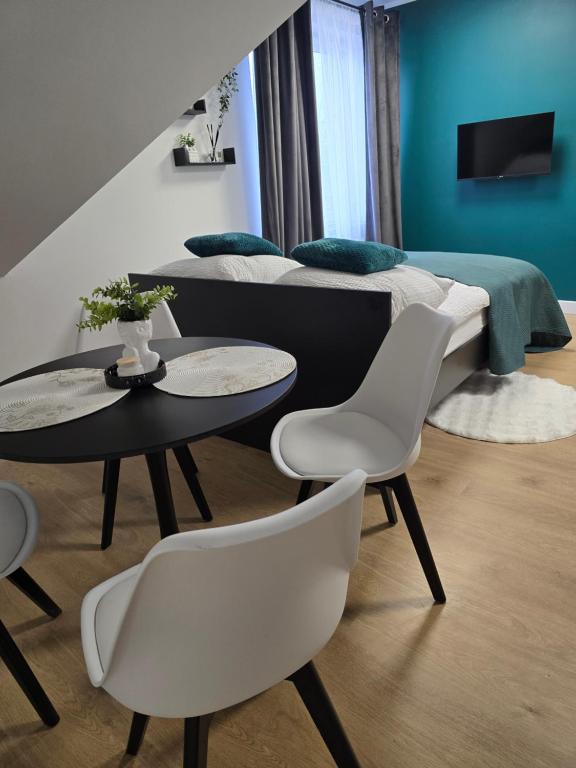 a bedroom with two beds and two tables and chairs at Apartamenty Nad Suwalskim Bulwarem in Suwałki