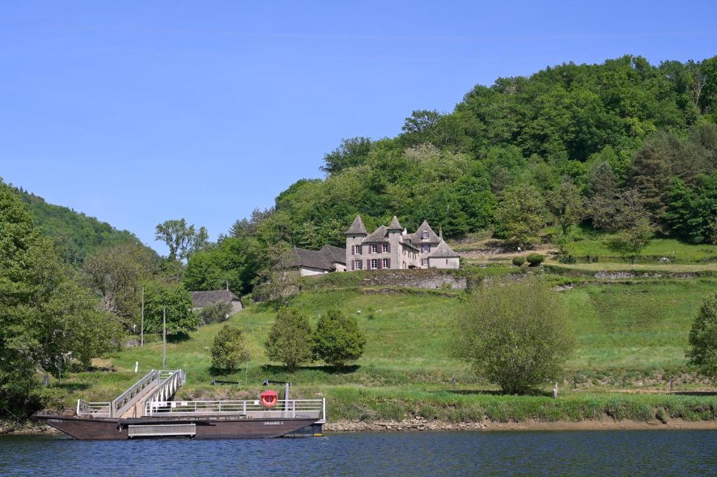 a house on a hill with a boat in the water at Castel de Grafeuille in Hautefage