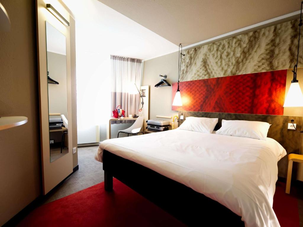 a bedroom with a large white bed with a red headboard at ibis Köln Centrum in Cologne