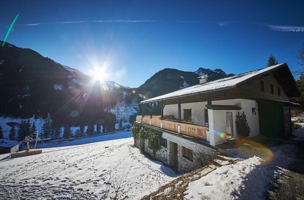 budynek w śniegu ze słońcem w tle w obiekcie Ferienhaus Oberlengau w Saalbach Hinterglemm