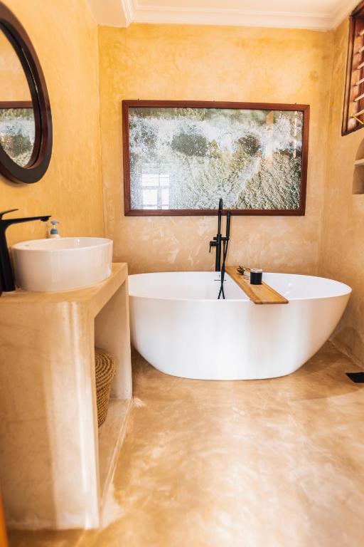 a bathroom with a large tub and a sink at Nyumbani Stonetown in Zanzibar City