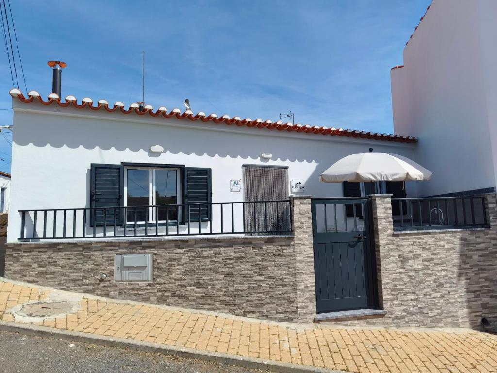 a white house with a balcony and a black door at O Refúgio in Mértola