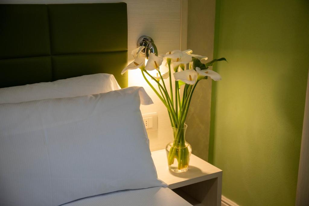 a vase with white flowers on a table next to a bed at Hotel Villa Irene & Spa in Rimini