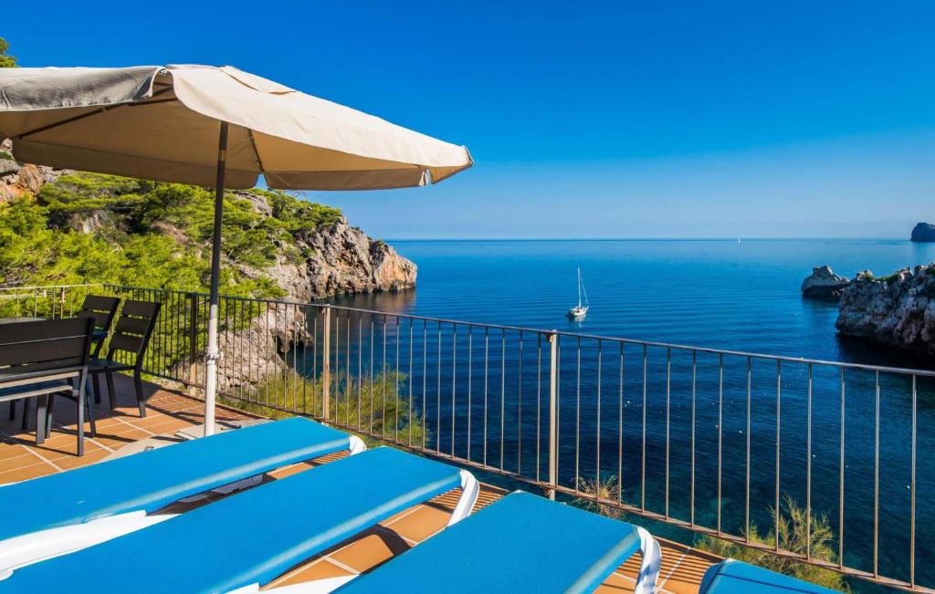 a balcony with chairs and an umbrella and the ocean at Amaret in Deia