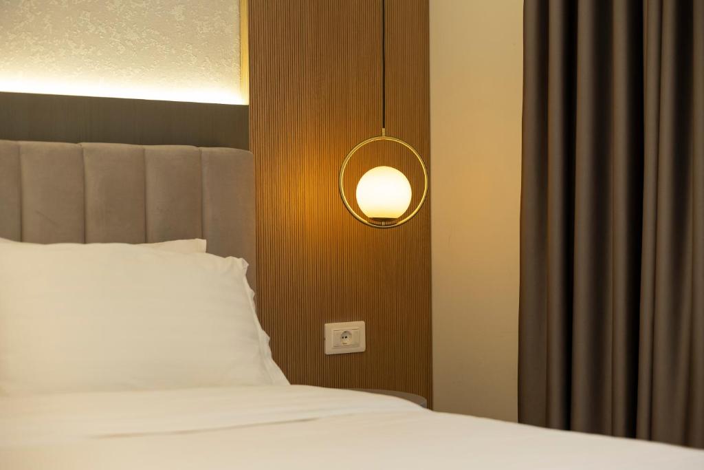 a bedroom with a white bed and a light at Hotel Vila e Arte City Center in Tirana