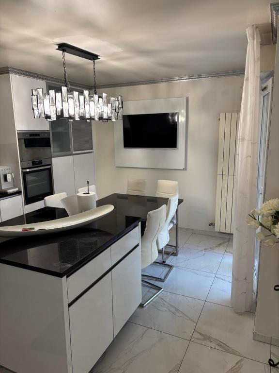 a kitchen with white cabinets and a black counter top at Villa Champigny in Champigny-sur-Marne