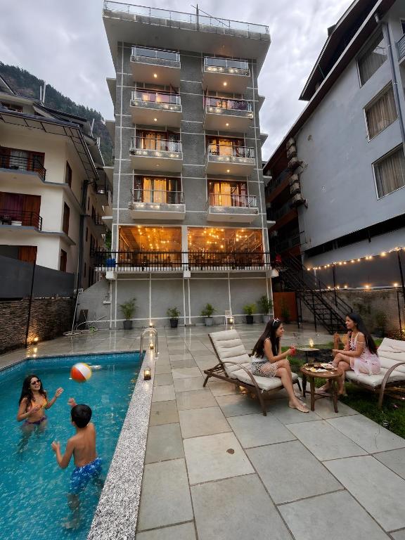 a group of people sitting around a swimming pool at Hotel Asiia Holiday with Swimming Pool -Central Heated and Air Cooled, Near mall road in Kasol