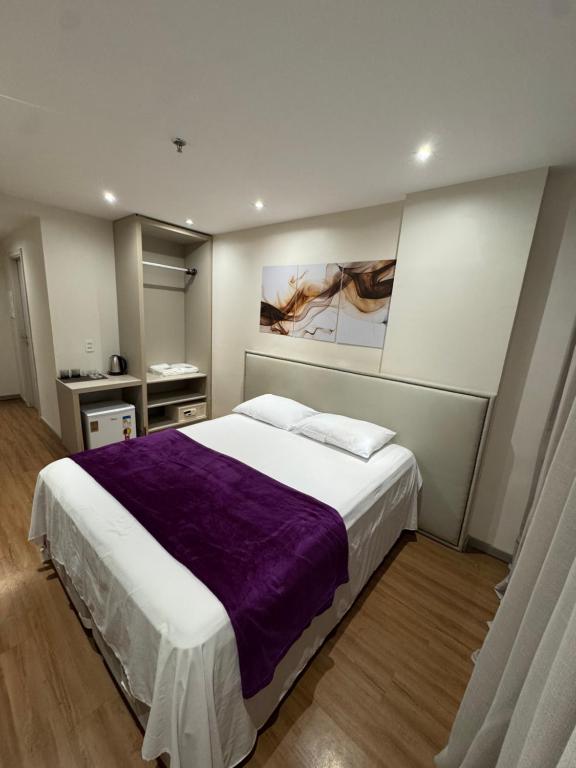 a bedroom with a large bed with a purple blanket at LUXO Premium Studio Pelinca in Campos dos Goytacazes