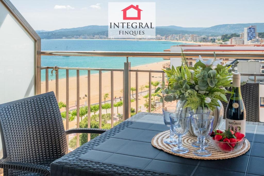a table with a bottle of wine and flowers on a balcony at Infinite View Palamós in Palamós
