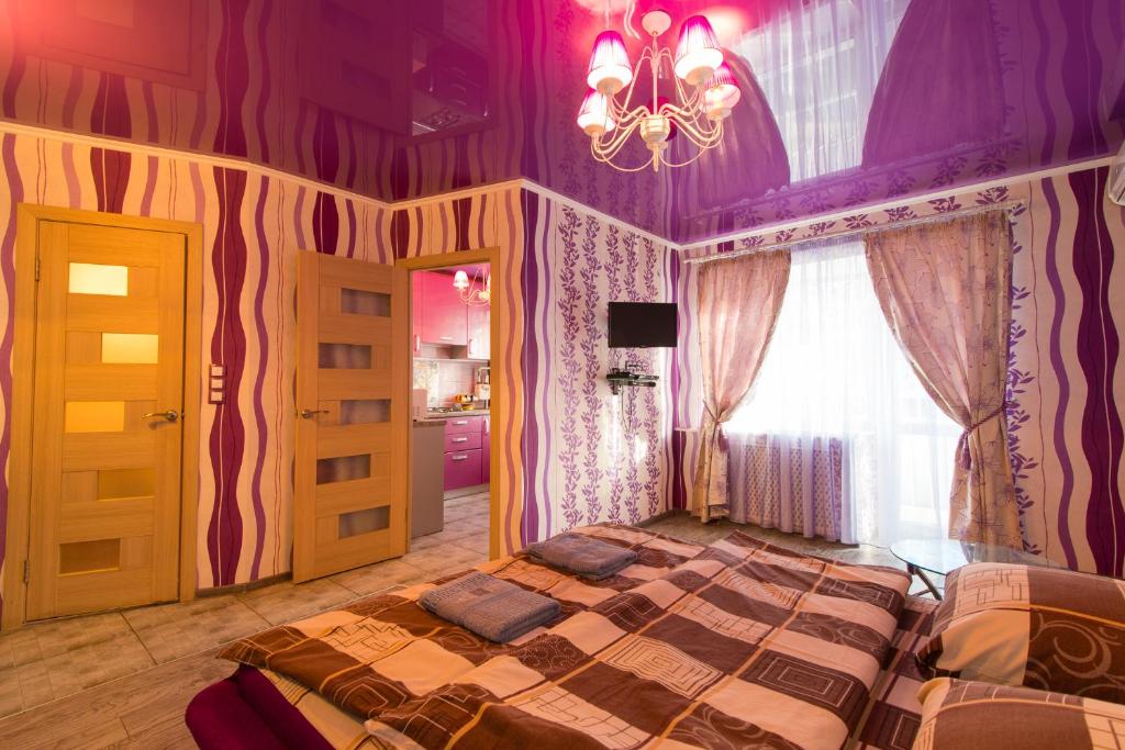 ヘルソンにあるCentral Supermarket Apartment 2019の紫の壁のベッド1台とシャンデリアが備わるベッドルーム1室