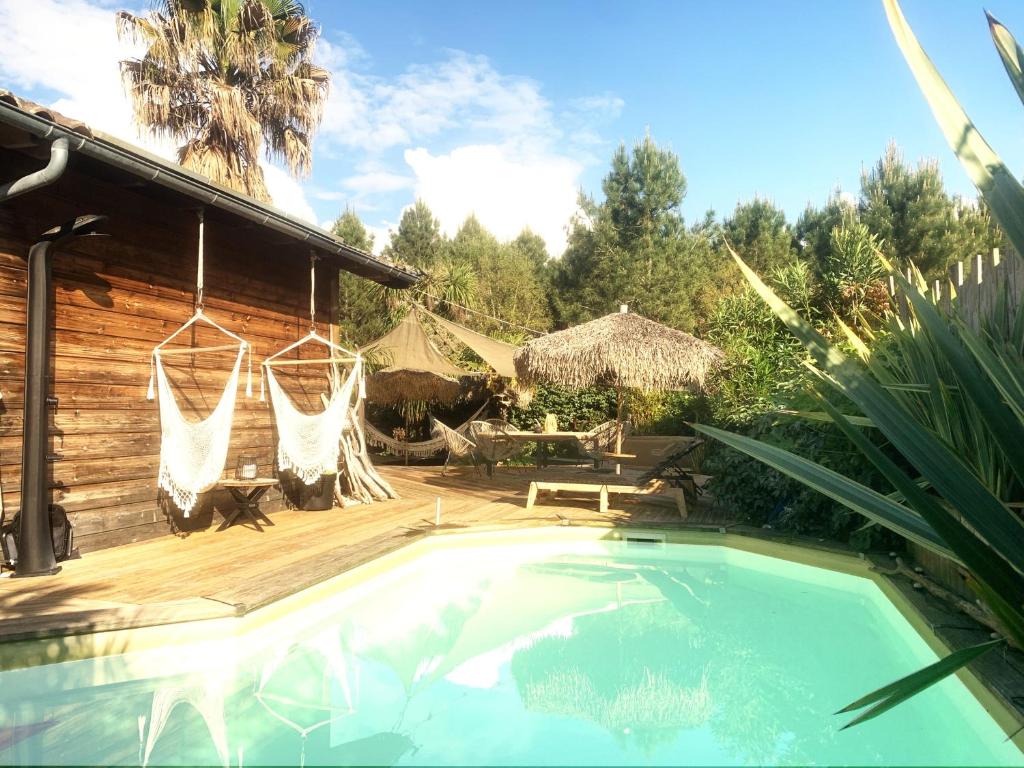 a backyard with a pool and a house with a hammock at Maison ambiance cabane exotique climatisée piscine & spa 3 chambres 6 personnes in Messanges