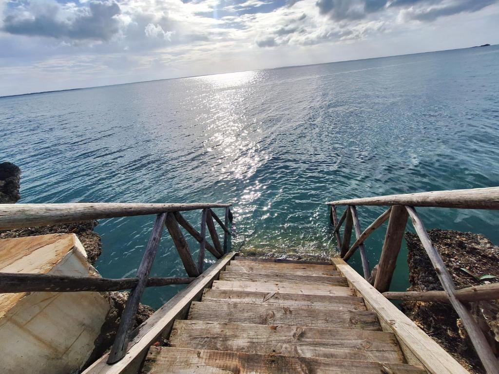 a wooden stairway leading to the ocean with a view at Bwereusunsetbungalow in Kidoti