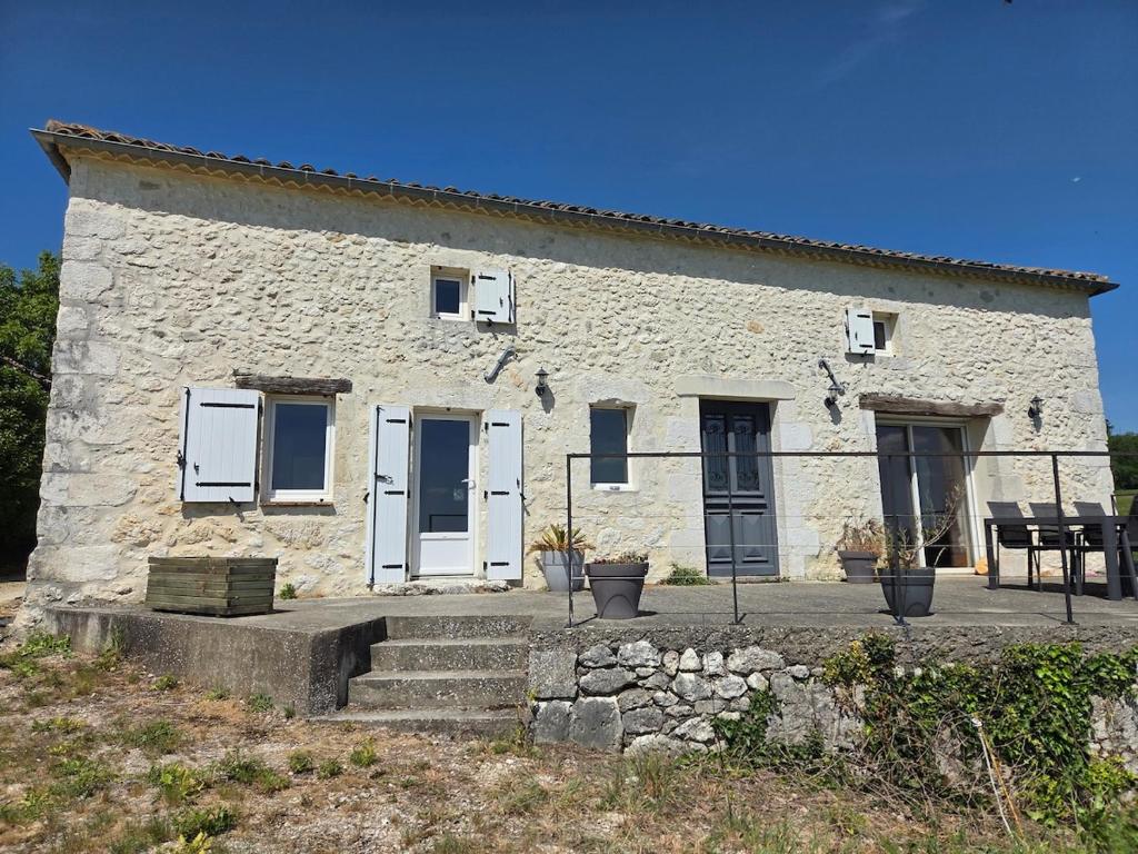 a stone building with white doors and windows at Maison de campagne in Eymet