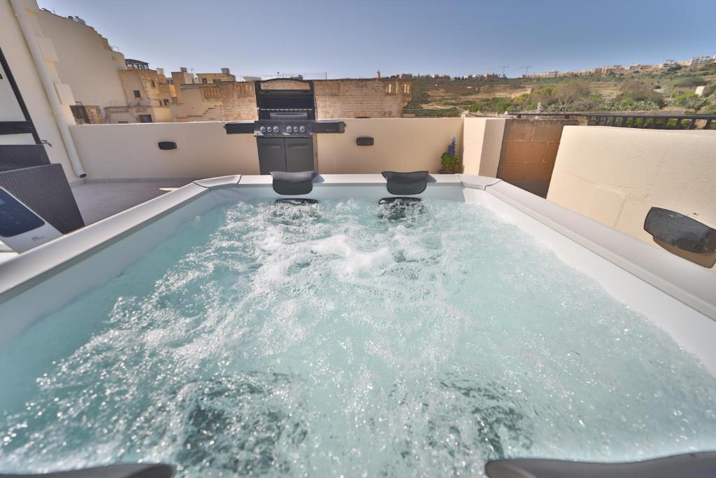 a hot tub on the roof of a building at Hot Tub With View, Stylish 3BR, Heart of Ghajnsielem in Għajnsielem