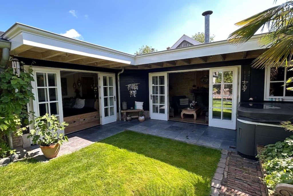 a house with a patio with a grass yard at Unique Accommodation in Twente with Jacuzzi in Borne