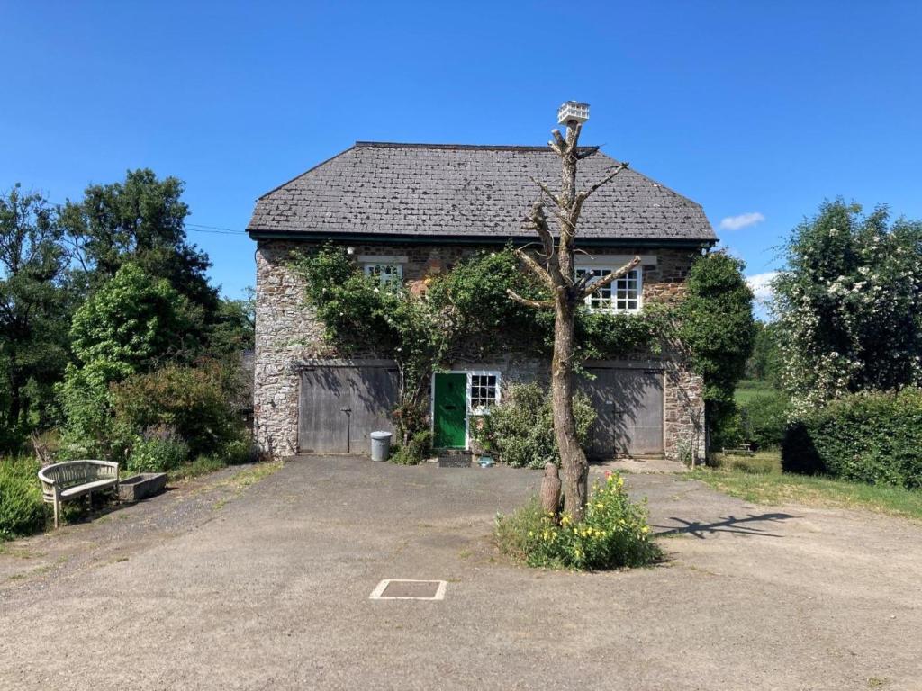 an old stone barn with a tree in front of it at 2 Bed in Beaworthy oc-77555 in Black Torrington