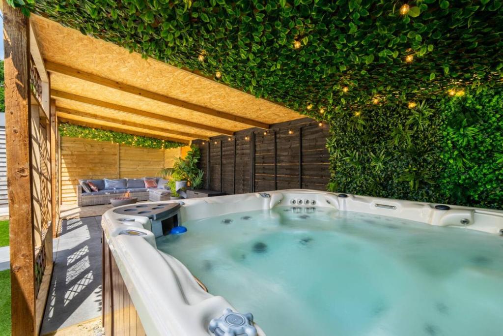 a hot tub on a patio with a green wall at The Cabin in Mountfield