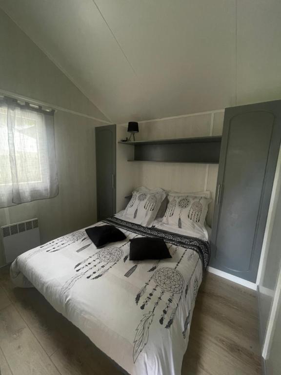 a bedroom with a bed with white sheets and pillows at Chalet cosy in Lissac-sur-Couze