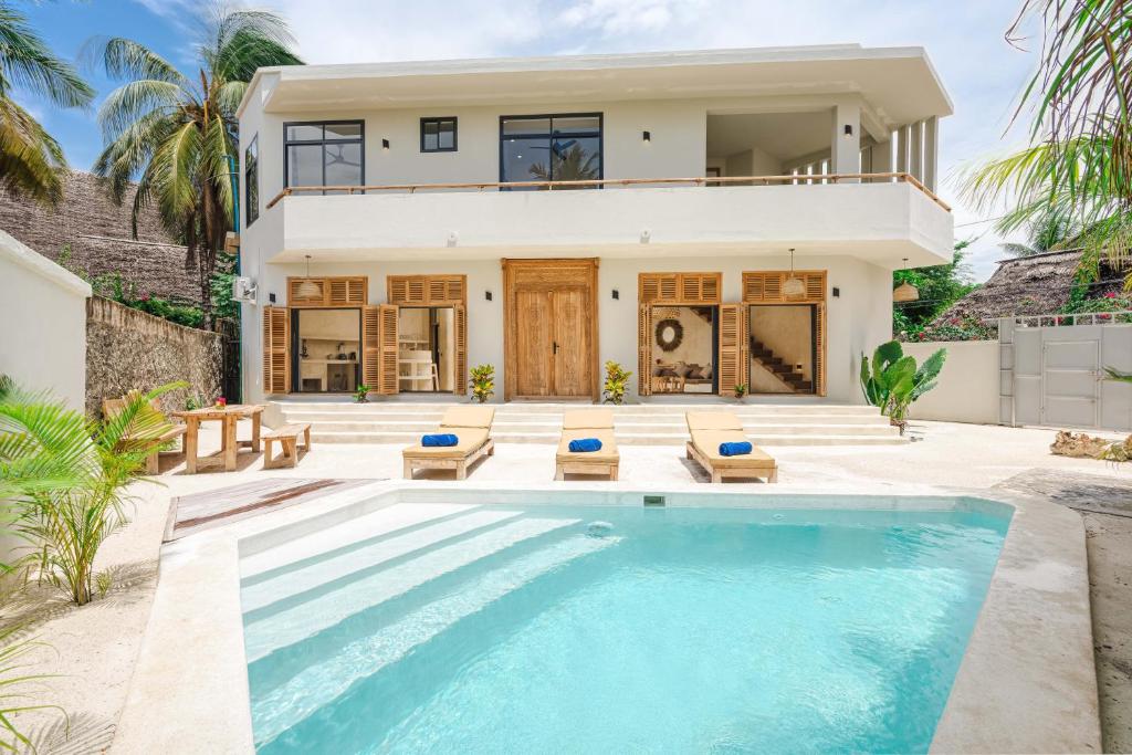 a villa with a swimming pool in front of a house at Nishati - Private Beach Villa in Matemwe